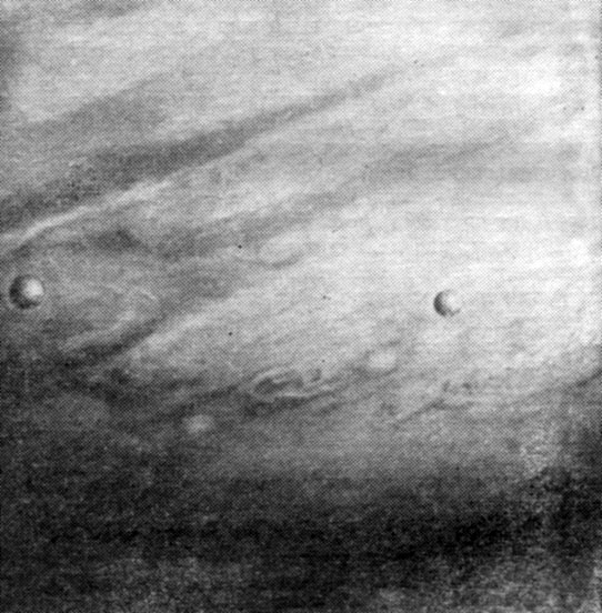 Рис 4. На фоне облачного покрова Юпитера проходят его спутники Ио (слева) и Европа. Снимок сделан 'Вояджером-1' 13 февраля 1979 г., когда он находился в 20 млн. км от планеты. Разрешение составляет около 400 км