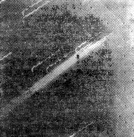 Рис. 12. 'Вояджеру-1' удалось сделать первый в истории снимок кольца Юпитера, шесть раз экспонировав в течение 11 мин один и тот же кадр. В результате изображение тускло светящегося кольца было зафиксировано как широкая светлая полоса, наискось пересекающая центр снимка. Зигзагообразные линии оставлены находящимися на заднем плане звездами вследствие движения космического аппарата. В момент съемки внешний край кольца был в 1 млн. 212 тыс. км от 'Вояджера'